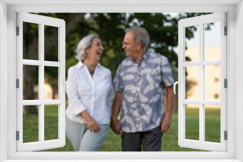 retired couple walking in a park smiling