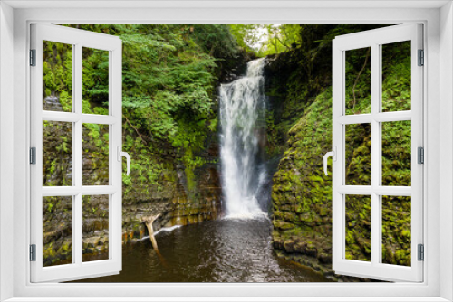 Fototapeta Naklejka Na Ścianę Okno 3D - Tall waterfall in a narrow canyon surrounded by green foliage (Sgwd Einion Gam, Waterfall Country, Wales)