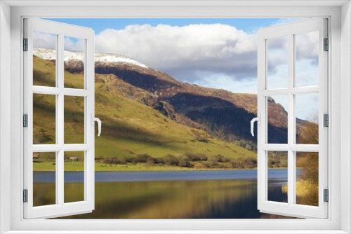 Winter sunshine on Llyn Mwyngil near the snow covered Cadair Idris in Snowdonia, Gwynedd, Wales, UK.