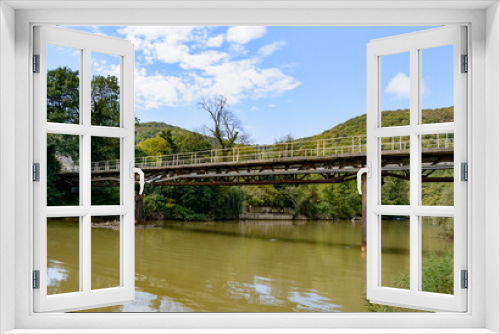 Fototapeta Naklejka Na Ścianę Okno 3D - Beautiful mountain range with a bridge over the river in summer against a blue sky with clouds. blurry focus
