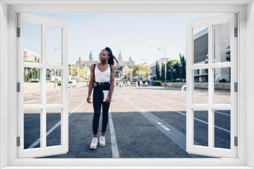 Beautiful african american hipster girl in casual wear standing on square in city on urban setting background, dark skinned female tourist walking on street looking at locations on leisure sunny day