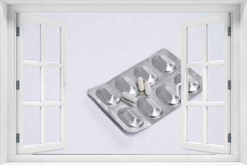 Fototapeta Naklejka Na Ścianę Okno 3D - Three white pills capsule lie on medicine in silver aluminium blister pack on white table. Isolated. Copy space. Top view. Concept pharmacy, medicine, healthcare, painkillers, drug, abuse