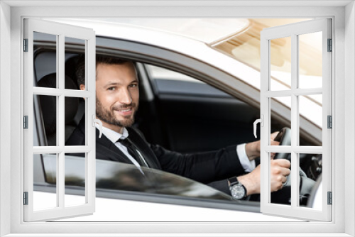 Cheerful successful businessman looking through car window