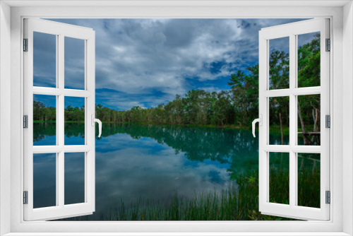 Fototapeta Naklejka Na Ścianę Okno 3D - Nature wallpaper The atmosphere along the natural reservoir is beautiful emerald green, surrounded by trees and various plants, with cool breezes.