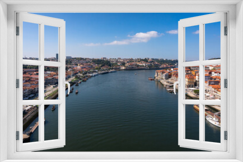 Fototapeta Naklejka Na Ścianę Okno 3D - Beautiful view of the banks of the Douro river in the city of Porto. A hill descending to the water with many colorful houses. Lots of cafes on the waterfront and wooden traditional boats at the pier.