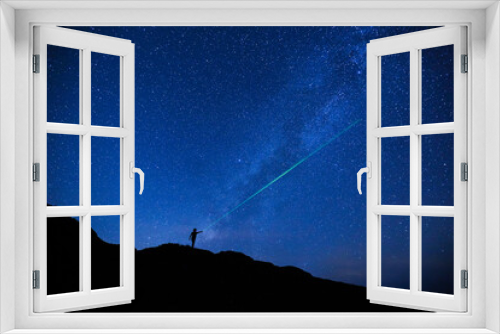 Fototapeta Naklejka Na Ścianę Okno 3D - Silhouette of girl / woman standing on the hill use a laser pointer to point at a star.  Stargazing at Oahu island, Hawaii. Starry night sky, Milky Way galaxy astrophotography.