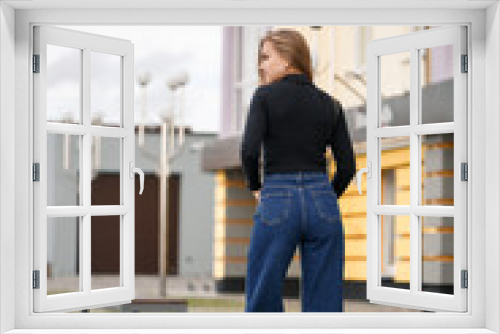 A beautiful girl with long hair in a black warm sweater. Young stylish woman in jeans culottes