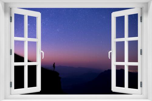 Fototapeta Naklejka Na Ścianę Okno 3D - Silhouette of young tourists standing and watching the view of star and milky way and sunrise alone on the top of the mountain before sunrise. He is happy to be with herself and nature.