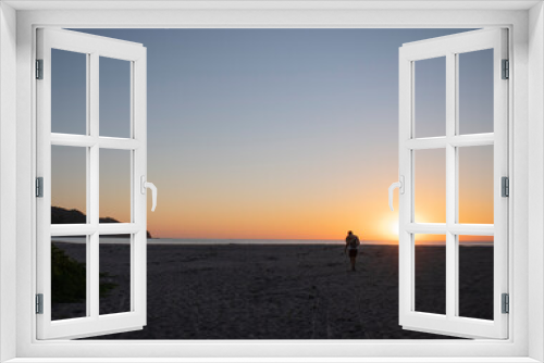 Fototapeta Naklejka Na Ścianę Okno 3D - man walking in the sunset on a beautiful beach with a blue sky