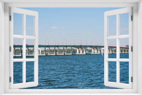 Fototapeta Naklejka Na Ścianę Okno 3D - A large concrete old bridge stands in a blue river, the sea against the background of the city and the sky.