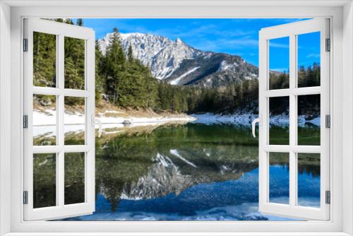 Fototapeta Naklejka Na Ścianę Okno 3D - Winter landscape of Austrian Alps with Green Lake in the middle. Powder snow covering the mountains and ground. Soft reflections of Alps in calm lake's water. Winter wonderland. Serenity and calmness