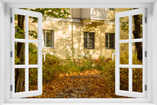 Fototapeta Naklejka Na Ścianę Okno 3D - The facade of a residential building surrounded by fallen leaves, autumn city view
