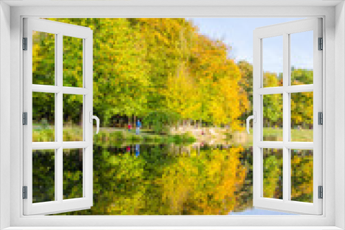 Fototapeta Naklejka Na Ścianę Okno 3D - Landscape with autumn park in the sunny day. Yellow and green trees are displayed with reflection on the lake.