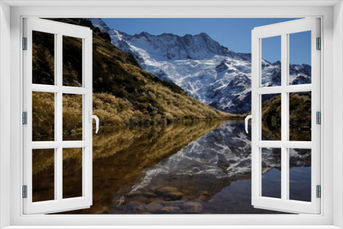 Fototapeta Naklejka Na Ścianę Okno 3D - Symmetrical picture of a snow covered mountain and yellow grasses reflecting in a lake at the Sealy Tarns viewpoint, Canterburry, New Zealand
