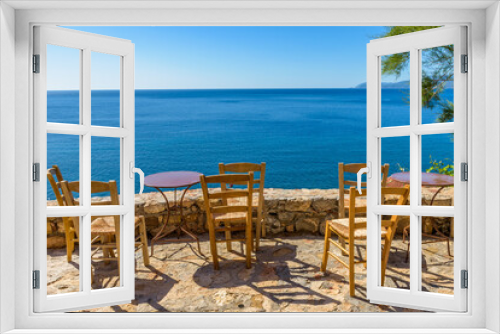 Fototapeta Naklejka Na Ścianę Okno 3D - Traditional cafe exterior in the fortified medieval  castle of Monemvasia. Iron tables and wooden chairs with the view of the  aegean sea in the background.