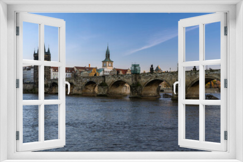 View of charles bridge and flowing river vltava in the center of prague at sunset the sky is blue in czech republic
