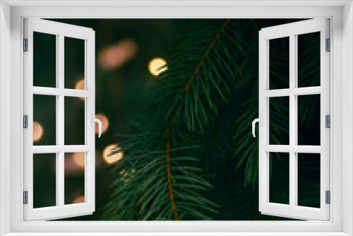 Fototapeta Naklejka Na Ścianę Okno 3D - Green Christmas tree branch and yellow lights garlands blurred in bokeh