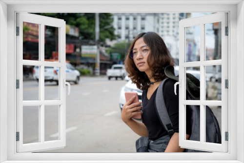 Female tourists are waiting for a taxi in the city by using the application in the smartphone to call a car