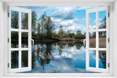 Fototapeta Naklejka Na Ścianę Okno 3D - blue sky reflections in clear water pond with spring trees and mirror water