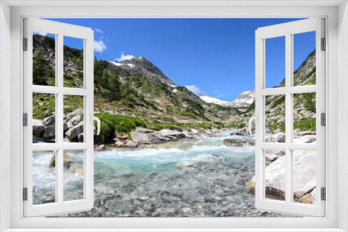 Fototapeta Naklejka Na Ścianę Okno 3D - A rushing torrent in the Austrian Alps. The meadow around it is overgrown with lush green grass. In the back there is a glacier. Sunny and bright day. Power of the nature. Remedy and serenity
