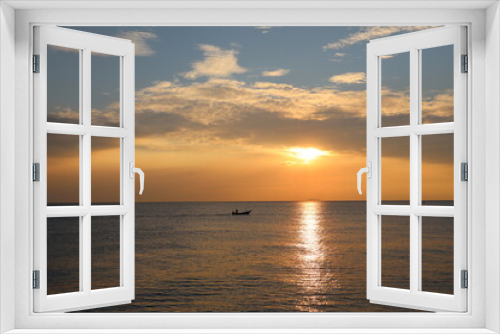 Orange Sunset at dawn with the wide view of sea and small boat floating on the ocean