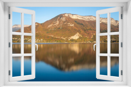 Fototapeta Naklejka Na Ścianę Okno 3D - View of the mountains, behind Lake Annecy, in Savoie in the French Alps. It is autumn, the sky is blue and sunny. Reflection on the water. Landscape.
