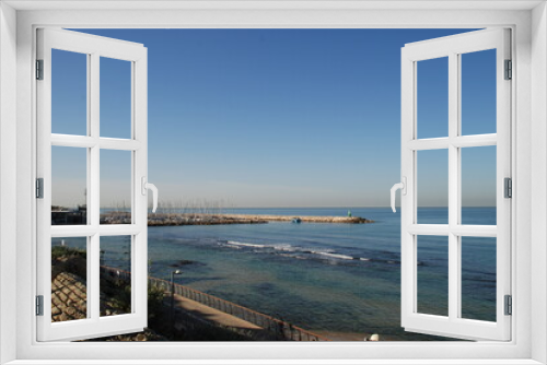 Fototapeta Naklejka Na Ścianę Okno 3D - Breakwater and pier on a calm sea
The Mediterranean Sea, blue water rolling in lazy waves ashore. In the distance there is a breakwater, which closes the pier with yachts from the waves. The sky is li