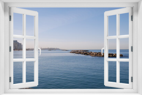 Fototapeta Naklejka Na Ścianę Okno 3D - Breakwater to the sea and the city in the distance.
Mediterranean Sea, sunny day. A stone breakwater in calm water, against the backdrop of a cityscape. Bright sky.