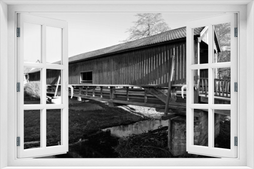 Fototapeta Naklejka Na Ścianę Okno 3D - Die überdachte , einspurige, aus dem Jahre 1818 stammende historische Holzbrücke bei Buchfart im Kreis Apolda. Die unter Denkmalschutz stehende Brücke überquert hier die Ilm -  Thüringen