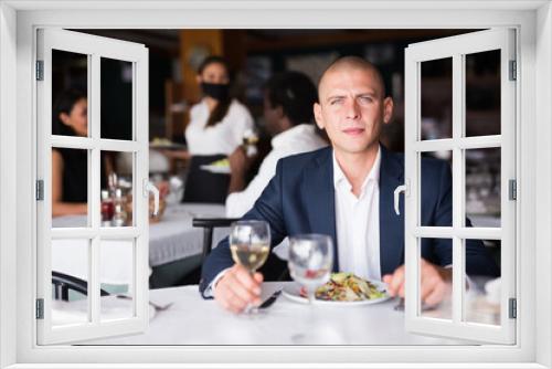 adult man thinking and eating in modern cafe