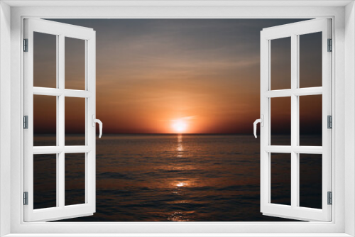 Fototapeta Naklejka Na Ścianę Okno 3D - Breathtaking summer sunset view on the beach. Wonderful sunset landscape at the deep dark sea and orange sky above it and calm waves are flowing on it.
