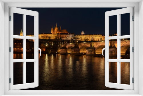 . prague castle and charles bridge and st. vita church lights from street lights are reflected on the surface of the vltava river in the center of prague at night in the czech republic