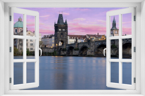 Charles Bridge on the Vltava River at sunset and colorful clouds and lights on the bridge in the early evening in the center of Prague