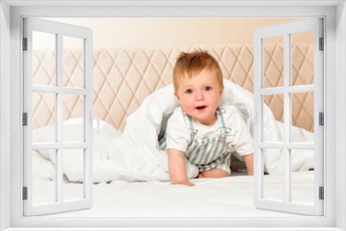 Happy cheerful baby in the interior of the bedroom. Laughter.