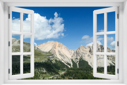 Fototapeta Naklejka Na Ścianę Okno 3D - A panoramic view on the valley in Italian Dolomites. Dense forest overgrows the mountains slopes. Lush green plants. High mountain chains in the back. Spring in the mountains. Sunny day. Serenity