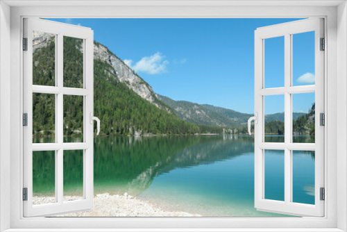 Fototapeta Naklejka Na Ścianę Okno 3D - A panoramic view on the Pragser Wildsee, a lake in South Tyrolean Dolomites. High mountain chains around the lake. The sky and mountains are reflecting in the lake. Dense forest at the shore. Serenity