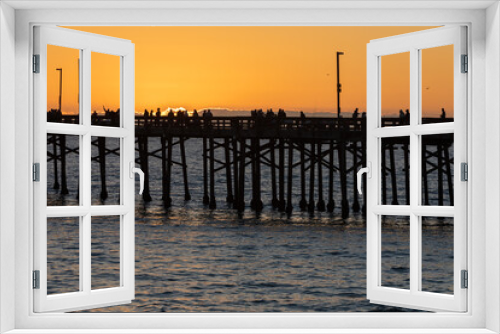 Fototapeta Naklejka Na Ścianę Okno 3D - Evening walkers and fishermen line the pier at sunset off the coast of Southern California on a cold winter's day.