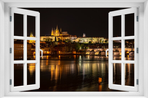View of the city of Prague with St. Vitus Cathedral on the hill, Charles Bridge and the Vltava river at night