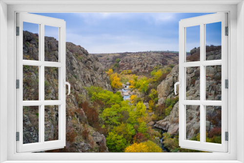 Fototapeta Naklejka Na Ścianę Okno 3D - A picturesque stream flows in the Aktovsky Canyon, surrounded by autumn trees and large stone boulders