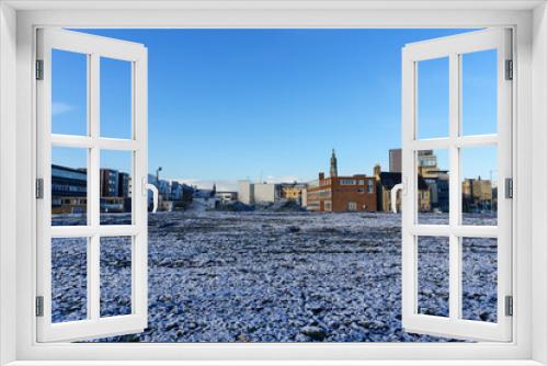 Fototapeta Naklejka Na Ścianę Okno 3D - Low view of ice covered ground and city buildings in the background