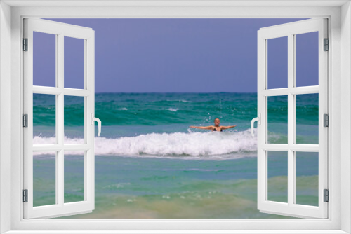 Fototapeta Naklejka Na Ścianę Okno 3D - A young beautiful girl jumps into the sea with happiness, rejoices in the waves