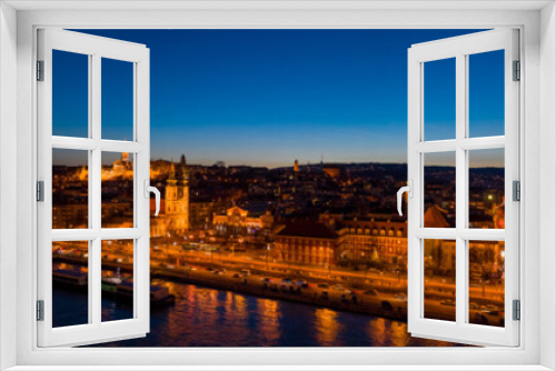 Aerial drone shot of St. Anne Parish church by Danube river at Budapest dusk city lights on