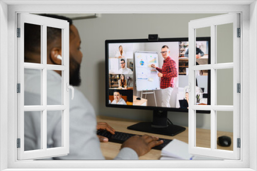 View over African guy shoulder using computer. PC screen view diverse people chatting via video call on the distant. App for remote communication with a many people in same time, virtual meeting