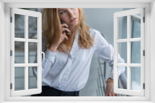 teenager talking on the phone. Beautiful with a lovely smile, webinar concept, on against the window, by the railing