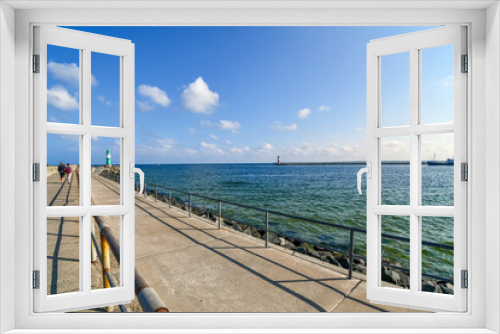 Fototapeta Naklejka Na Ścianę Okno 3D - Two lighthouses, one green and one red are visible from the promenade boardwalk along the Baltic Sea coast at the town of Warnemunde, Germany.