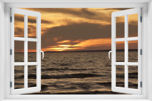 Fototapeta Naklejka Na Ścianę Okno 3D - Calm sea at sunset. The water has no big waves and the sky is coloured in orange and yellow. The water is dark. The image is suitable for wallpapers.