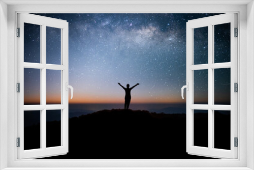 Fototapeta Naklejka Na Ścianę Okno 3D - Silhouette of young traveler watched the star and milky way on top of the mountain alone before sunrise. He raised his arms over his head, expressing his joy and success, and enjoyed his hike.