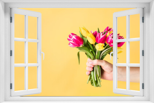 Fototapeta Naklejka Na Ścianę Okno 3D - Male hand holding beautiful fresh pink and yellow tulips bouquet on light yellow background. Greeting card mockup. Birthday, Valentines day, mother's and woman's day. Selective focus. Copy space.