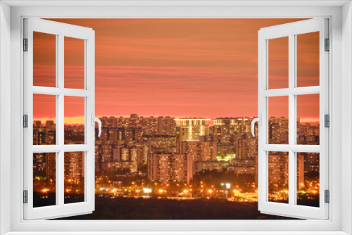 Windows of the night city building and roads with cars. Pink evening sunset over modern Moscow, Russia