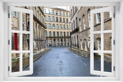 Fototapeta Naklejka Na Ścianę Okno 3D - Looking along, Vicar Lane, with Victorian stone built mills, on a wet day in, Little Germany, Bradford, UK